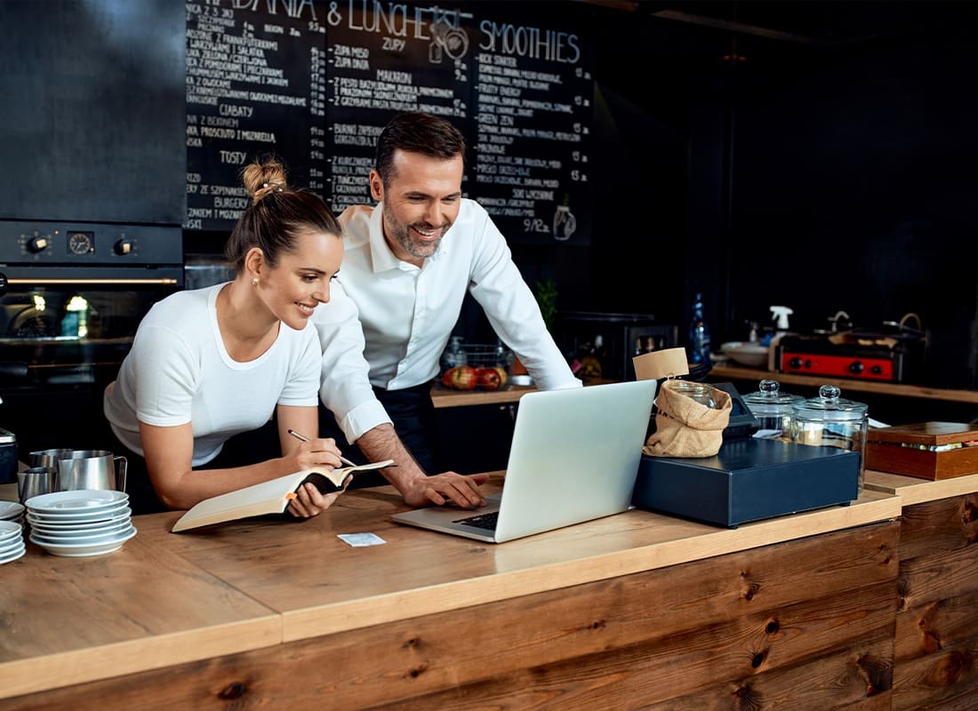 Insurance Solutions - Happy Small Business Owners Working With Laptop at Cafe